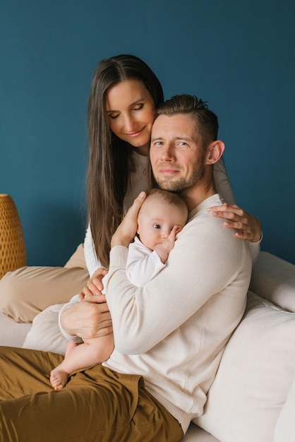 Retrato de una familia joven feliz con su pequeño hijo en los brazos de papá en la casa