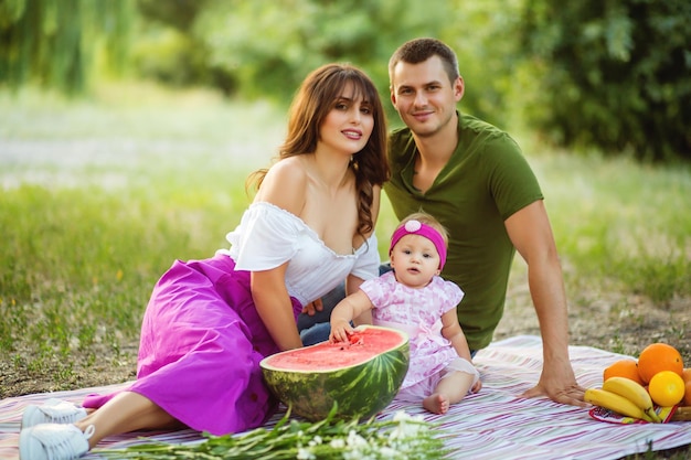 Retrato de una familia joven con una hija recién nacida en un picnic