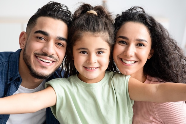 Foto retrato de familia joven. linda niña tomando una foto selfie con sus padres árabes en casa, feliz mamá, papá e hija divirtiéndose juntos, mirando y sonriendo a la cámara, toma de primer plano