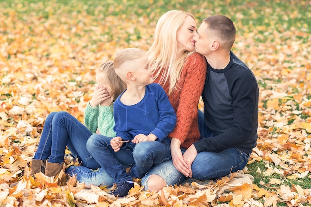 Retrato de familia joven sentada en hojas de otoño