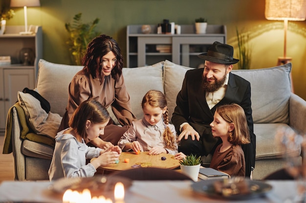 Retrato de una familia judía moderna jugando al tradicional juego de dreidel en un hogar acogedor