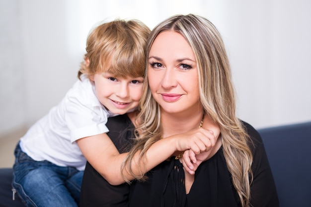 Retrato de familia - lindo hijo abrazando a su joven madre en casa