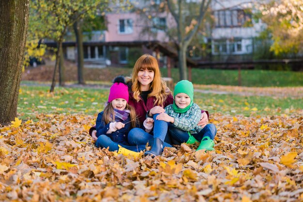 Retrato de familia de mujer y niños sentados en el follaje