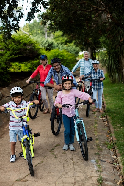Retrato de familia multigeneración de pie con bicicleta en el parque