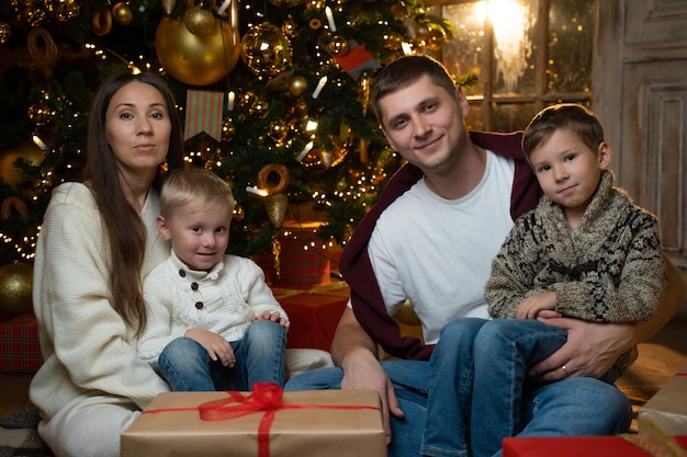 Retrato de familia de Navidad familia sentada en el piso frente al hermoso árbol de Navidad