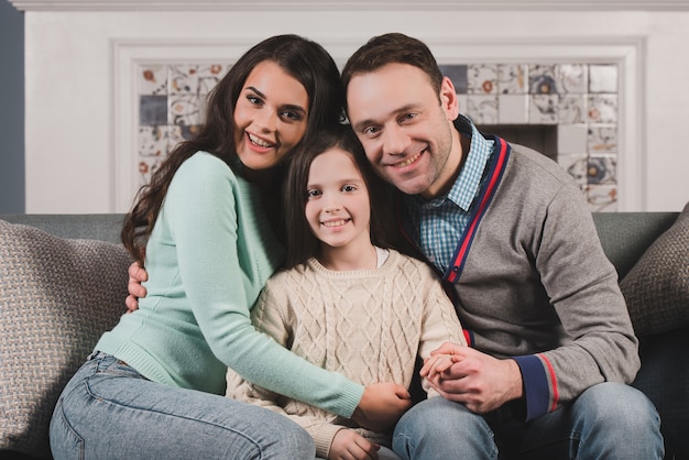 Retrato de familia de padres felices y su hija en casa