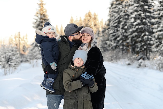 Un retrato de una familia parada en la nieve donde el padre sostiene a un niño pequeño en sus brazos y su esposa e hijo están junto a él el concepto de una familia feliz en la nieve