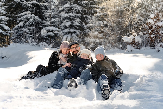 Un retrato de una familia parada en la nieve donde el padre sostiene a un niño pequeño en sus brazos y su esposa e hijo están junto a él el concepto de una familia feliz en la nieve