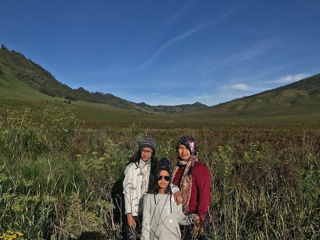 Foto retrato de una familia de pie en el campo contra el cielo azul