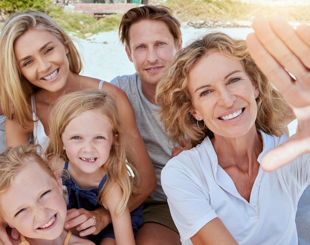 Retrato de una familia relajada que se relaja y se une en la playa Dos niñas alegres que pasan tiempo con sus padres y su abuela en unas vacaciones en la playa Familia tomándose una selfie juntos