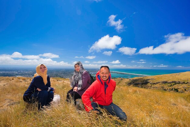 Foto retrato de una familia sentada en la montaña contra el cielo azul durante un día soleado