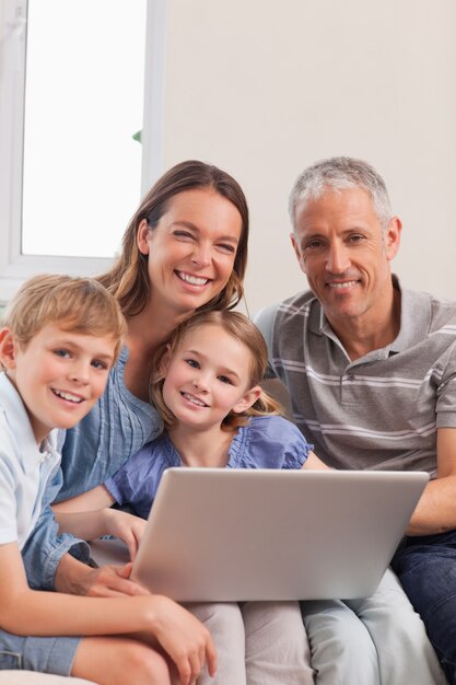 Retrato de una familia sentada en un sofá con una computadora portátil