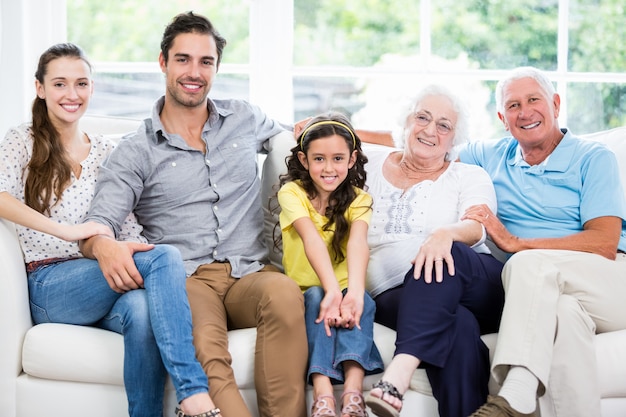 Retrato de familia sonriente con abuelos en sofá