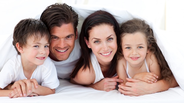 Retrato de una familia sonriente acostada en la cama