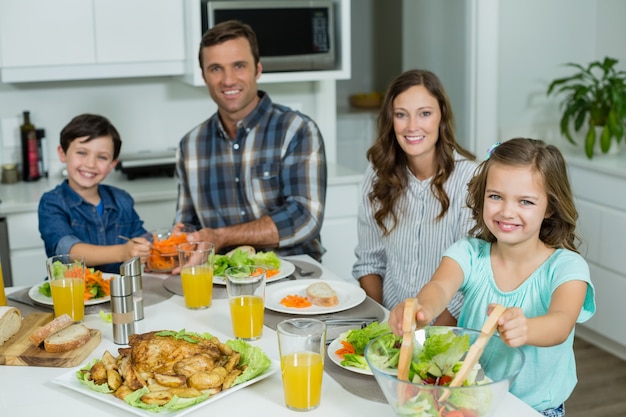 Retrato de familia sonriente almorzando juntos en la mesa de comedor