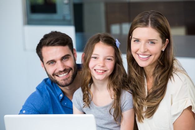 Retrato de familia sonriente con laptop