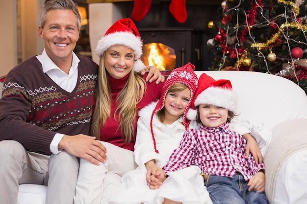 Retrato de una familia sonriente sentada en el sofá en el tiempo de Navidad en casa en la sala de estar