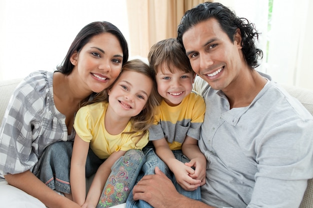 Retrato de una familia sonriente sentada en el sofá