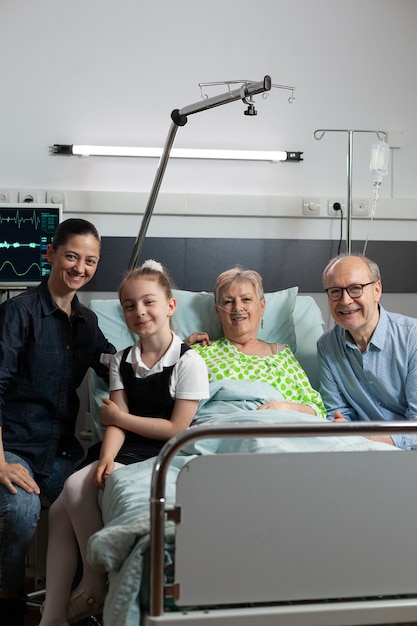 Retrato de familia visitando pensionista abuela jubilada mirando a la cámara