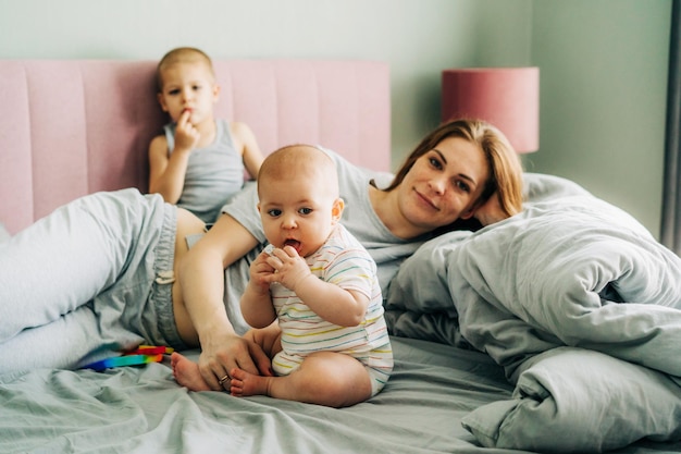 Retrato familiar de la madre con los niños en el dormitorio en la cama