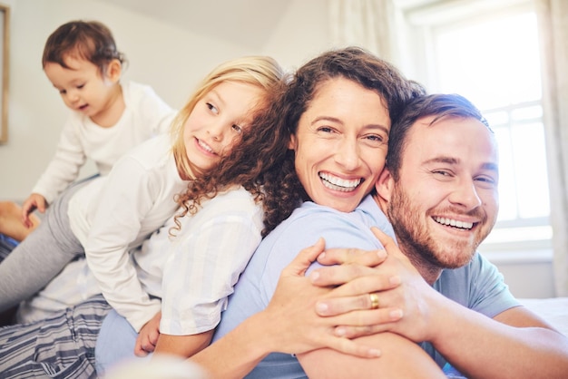 Foto retrato familiar y sonrisa feliz en un dormitorio de casa con hijos y padres juntos en la cama por tiempo de calidad hombre y mujer o madre y padre con hijos por felicidad, amor y cuidado por la mañana