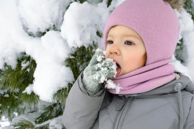 Foto retrato fechado de uma linda garotinha lambendo flocos de neve ao ar livre no inverno