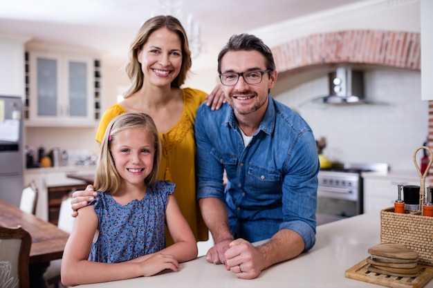 Retrato de felices padres e hija en la cocina