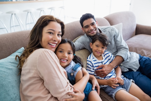 Retrato de felices padres y niños sentados en el sofá en la sala de estar