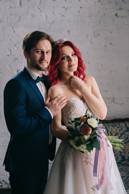 Retrato de felices recién casados que ríen y se abrazan en una habitación estilo loft