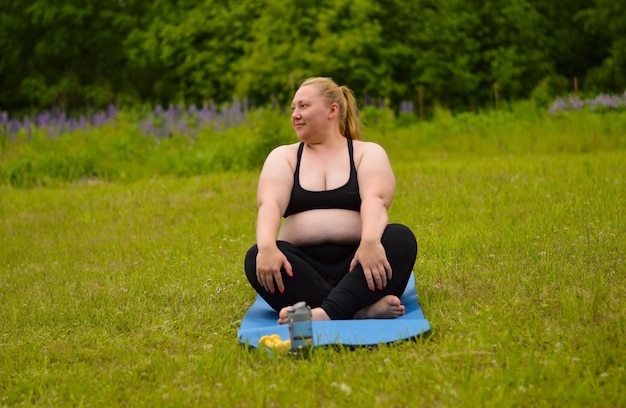 Retrato de felicidad mujer de talla grande practicando yoga al aire libre