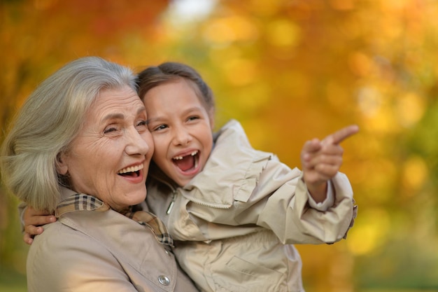 Retrato de feliz abuela y nieta posando al aire libre en otoño