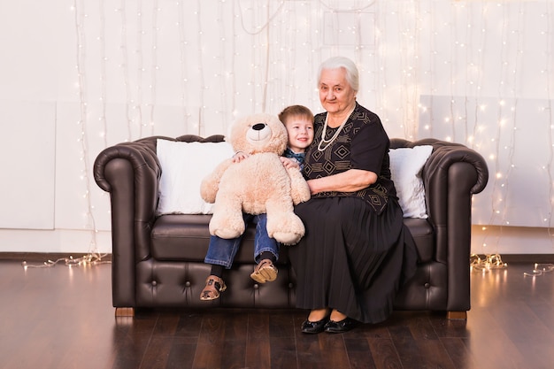 Retrato de feliz abuelita y su nieto abrazando, mirando a cámara y sonriendo