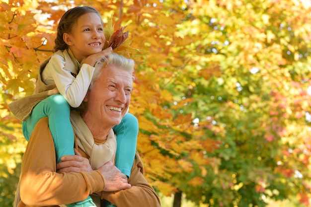 Retrato de feliz abuelo y nieta posando al aire libre en otoño