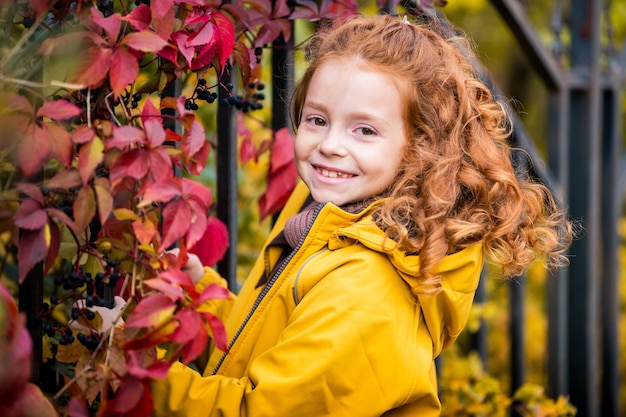 Retrato de una feliz y alegre adolescente rizada pelirroja en la naturaleza entre el brillante bosque de otoño