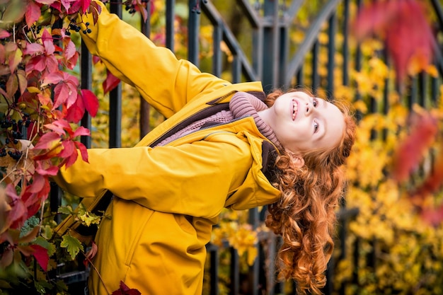 Retrato de una feliz y alegre adolescente rizada pelirroja en la naturaleza entre el brillante bosque de otoño