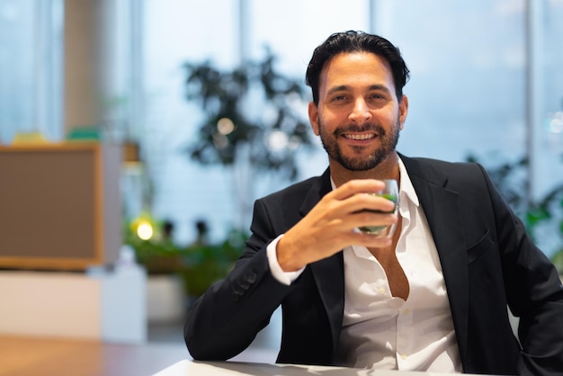 Retrato de feliz y apuesto hombre de negocios hispano en una cafetería tomando té verde