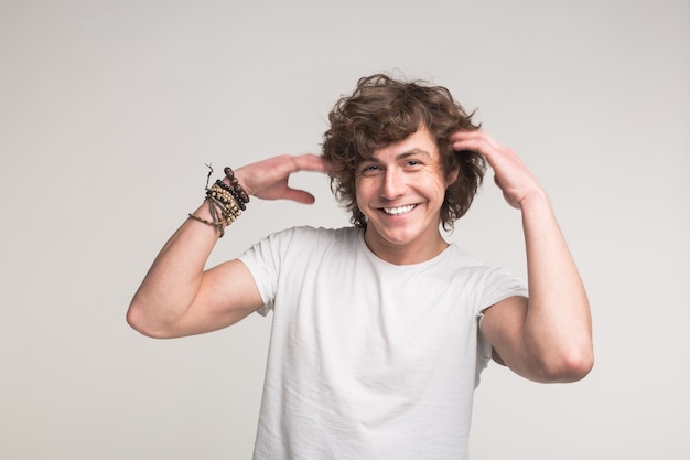 Retrato de feliz apuesto joven en camiseta blanca con manos levantadas en estudio