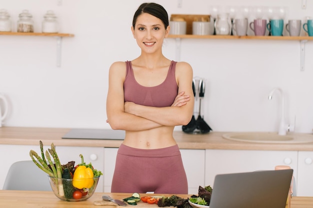 Retrato de feliz bloguera deportiva en la mesa con verduras frescas concepto de alimentación saludable