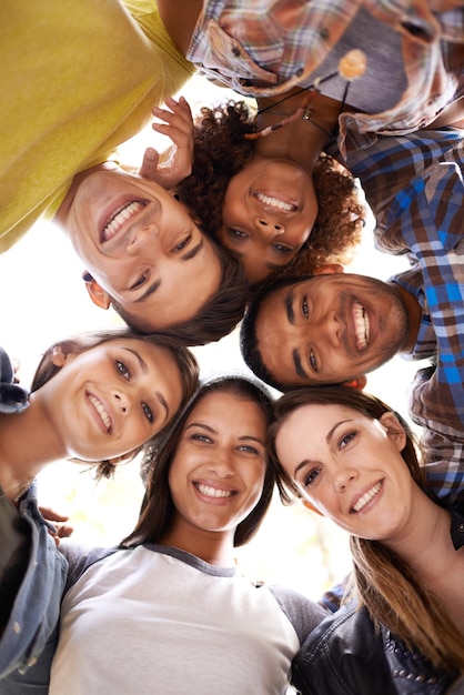 Foto retrato feliz e baixo ângulo de amigos em círculo com diversidade, unidade e colaboração sorriso de trabalho em equipe e grupo de pessoas multirraciais reunidas para solidariedade, comunidade e amizade