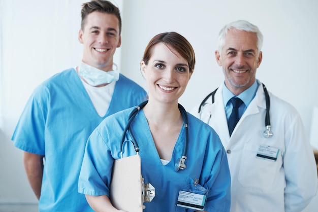 Retrato feliz e médico com enfermeiros em hospital com clipboard para pesquisa médica em colaboração Lista de verificação de sorriso e cirurgião masculino sênior com profissionais de saúde na clínica para trabalho em equipe