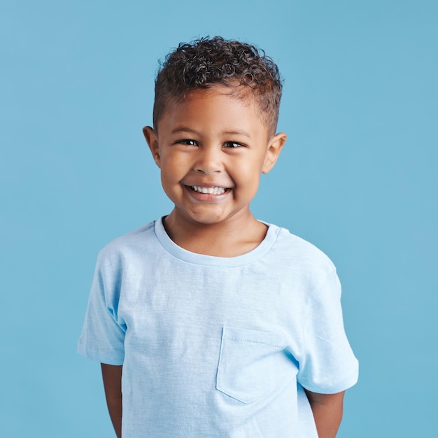 Foto retrato feliz e uma criança com um sorriso para atendimento odontológico isolado em um fundo azul em um estúdio smile jardim de infância e um garotinho sorrindo de felicidade sobre os resultados da higiene oral jovem