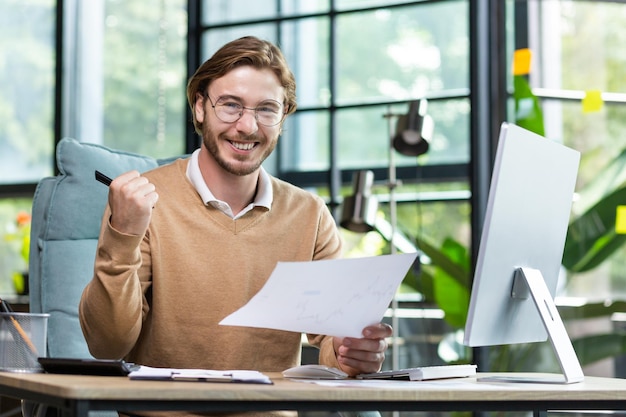 Retrato feliz empresario financiero hombre con raza mirando a la cámara y sonriendo sosteniendo informe