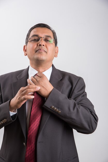 Retrato de feliz empresario indio o asiático de mediana edad en traje negro con signo de éxito mientras está de pie aislado sobre fondo blanco.