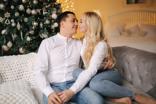 Retrato de feliz esposo con su encantadora esposa abrazos en casa durante las vacaciones de Navidad.