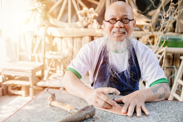 Retrato feliz fabricante de cuero artista artesanal trabajando en su propio taller pequeño estudio hecho por pedido obra maestra