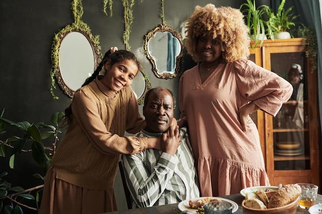 Retrato de una feliz familia africana de tres sonriendo a la cámara mientras cenaba en familia en casa