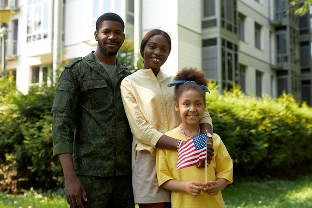 Retrato de una feliz familia afroamericana con un padre militar sonriendo a la cámara durante el Día de la Independencia