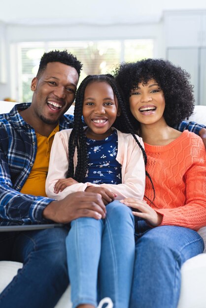 Foto retrato de una feliz familia afroamericana sentada en el sofá en el espacio de copia de casa