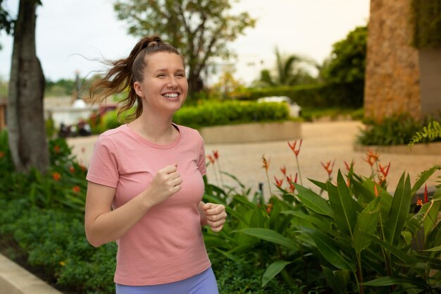 Retrato de una feliz y hermosa joven corredora está corriendo al aire libre trotando haciendo ejercicio afuera en