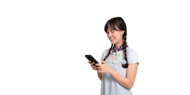 Retrato de feliz y hermosa mujer asiática joven en vestido de mezclilla usando un teléfono inteligente en una foto de estudio de fondo blanco